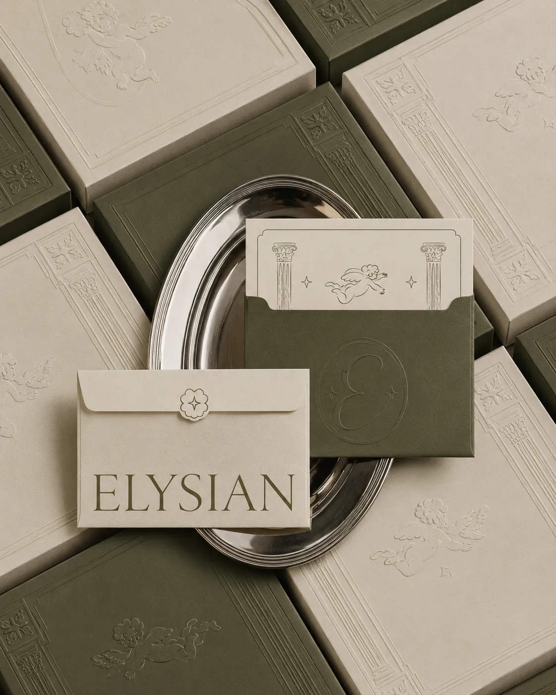 Elysian envelopes and cards on a silver tray over embossed boxes